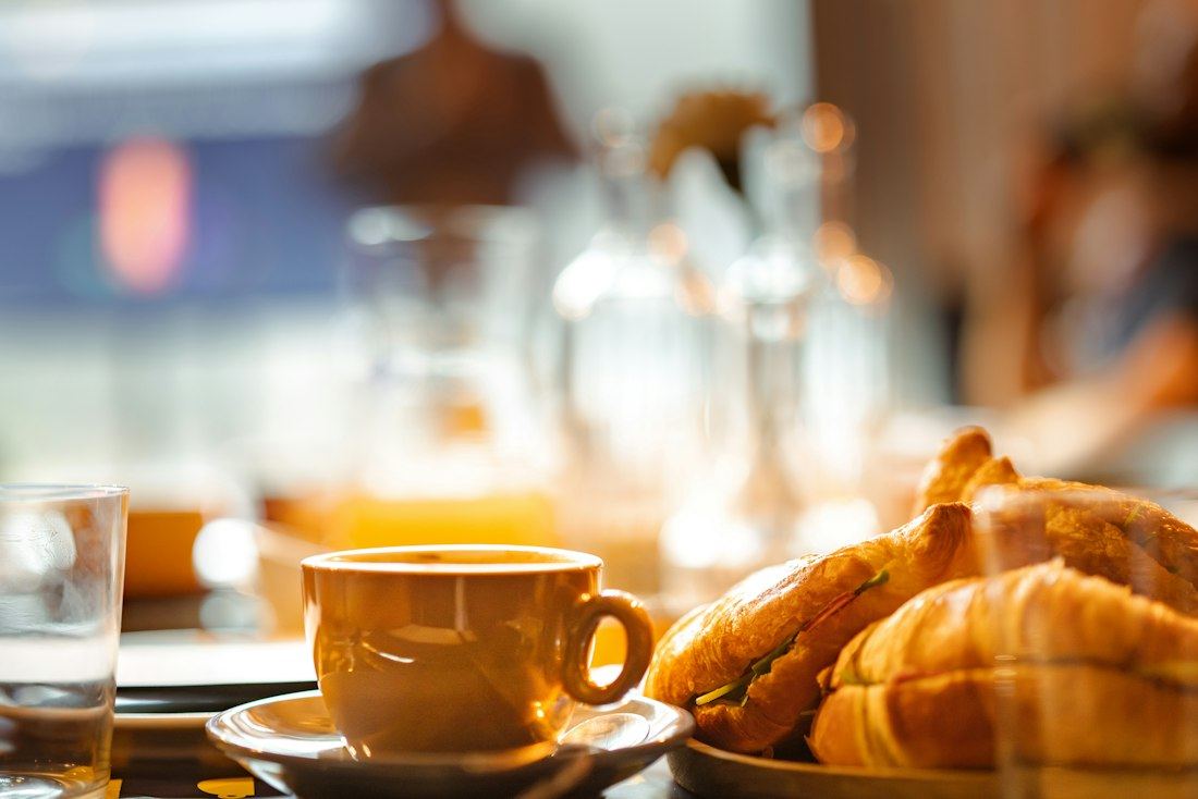 Taza de café y medialunas sobre la mesa del desayuno