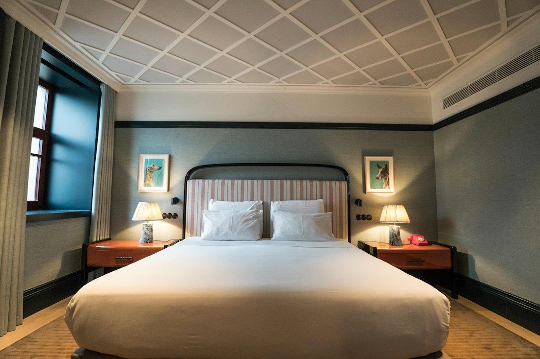 Habitación doble con cama matrimonial, cielorraso ornamentado y mesitas de luz de madera