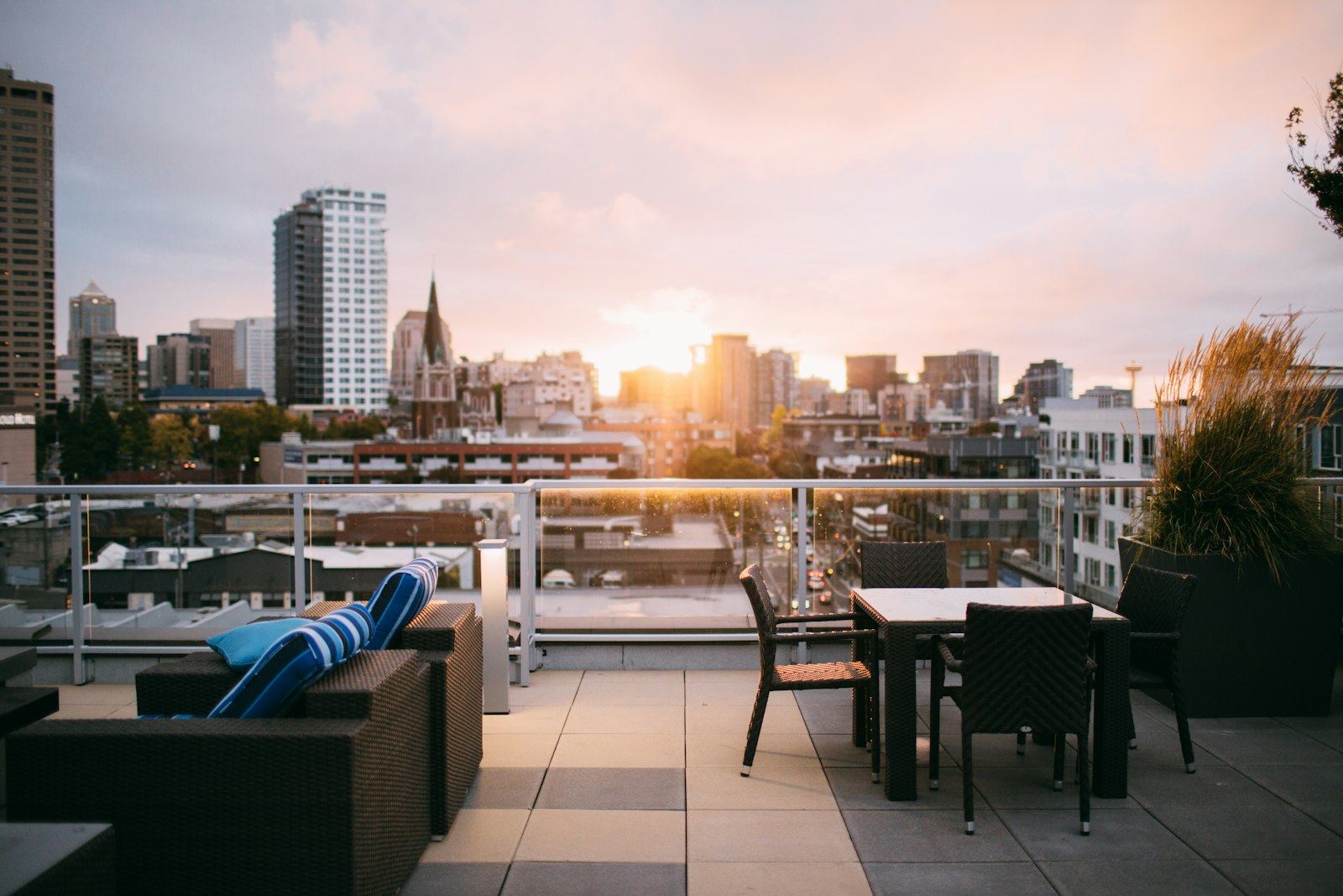 Terraza con mesas y sillones frente a los edificios de la ciudad al atardecer